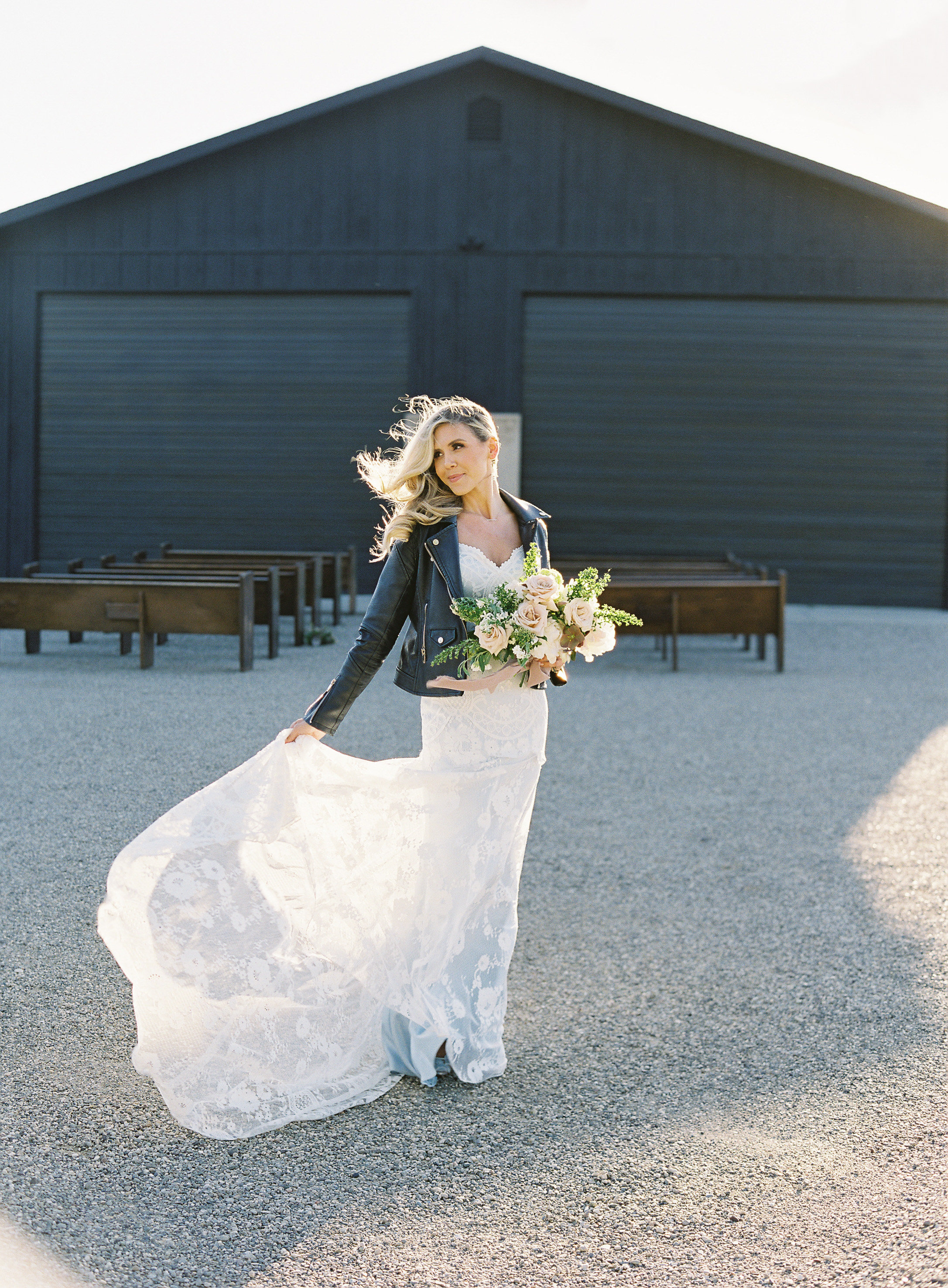 Bride at a barn venue with a trailing bouquet